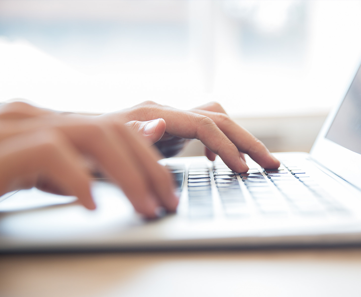 close up of hands typing on laptop keyboard